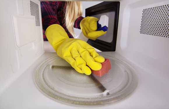 Woman cleaning microwave from inside. 