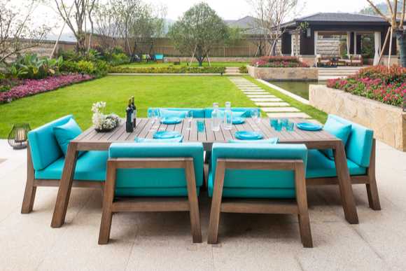 A dining table on a patio with very large chairs