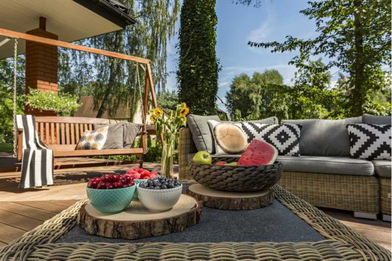 Outdoor patio with patterned pillows and bowls of fruit.