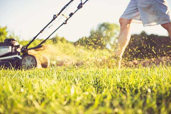 closeup of man mowing lawn with push mower