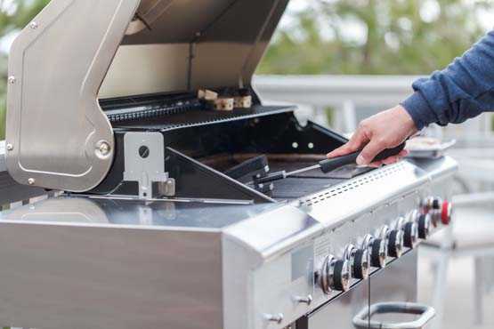 Person scrubbing grill with brush. 