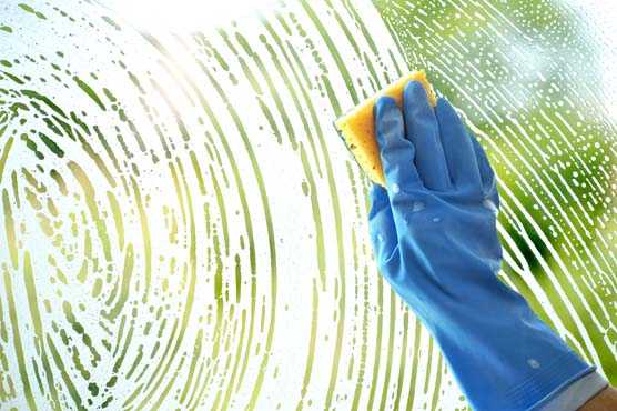 Rubber gloved hand cleaning window with sponge. 