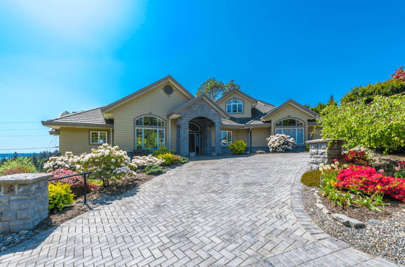 Long clean driveway leading up to large house.