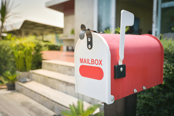 Red mailbox that says “mailbox” in front of house.