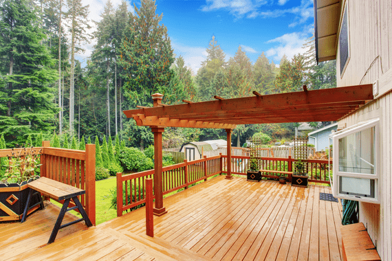 Large wooden deck leading to forested backyard.
