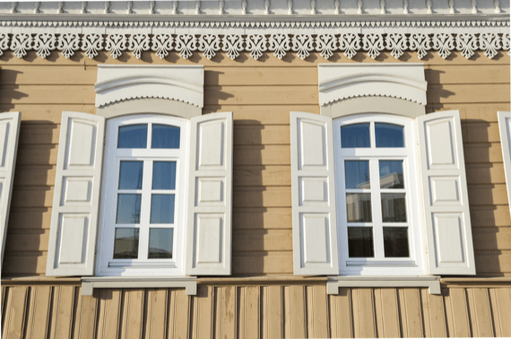 White window trim and shutters on a tan home.