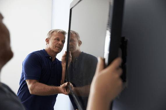 Man installing a flat screen tv onto a wall mount.