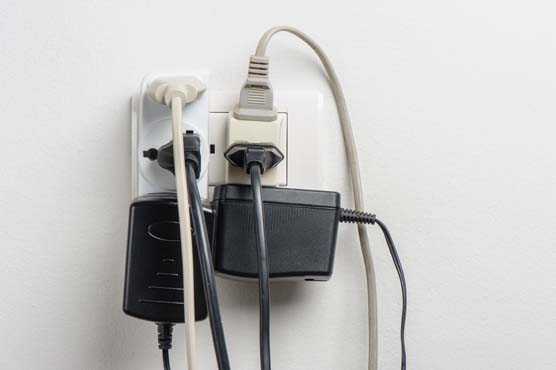 Wall power outlet completely filled with different types of plugs. 