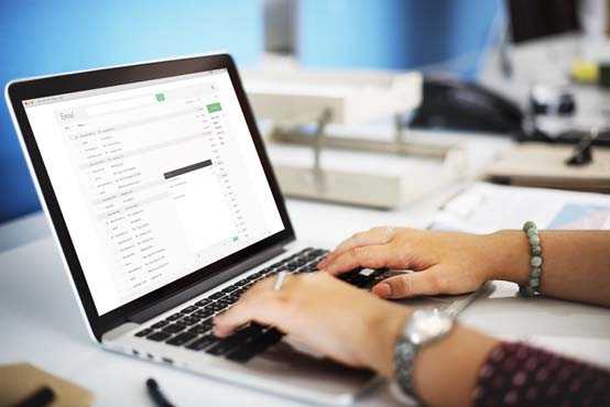 Woman’s hand on laptop with a email inbox on screen.