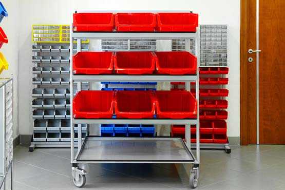 Red buckets on a rolling shelving unit in a well organized garage. 
