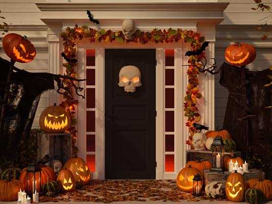 Front door decorated for Halloween with leaves, pumpkins, skeletons and candles.