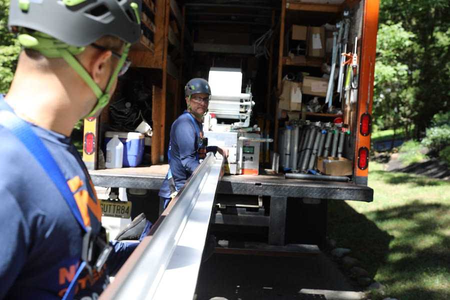 Two Ned Stevens professionals holding a new gutter for installation