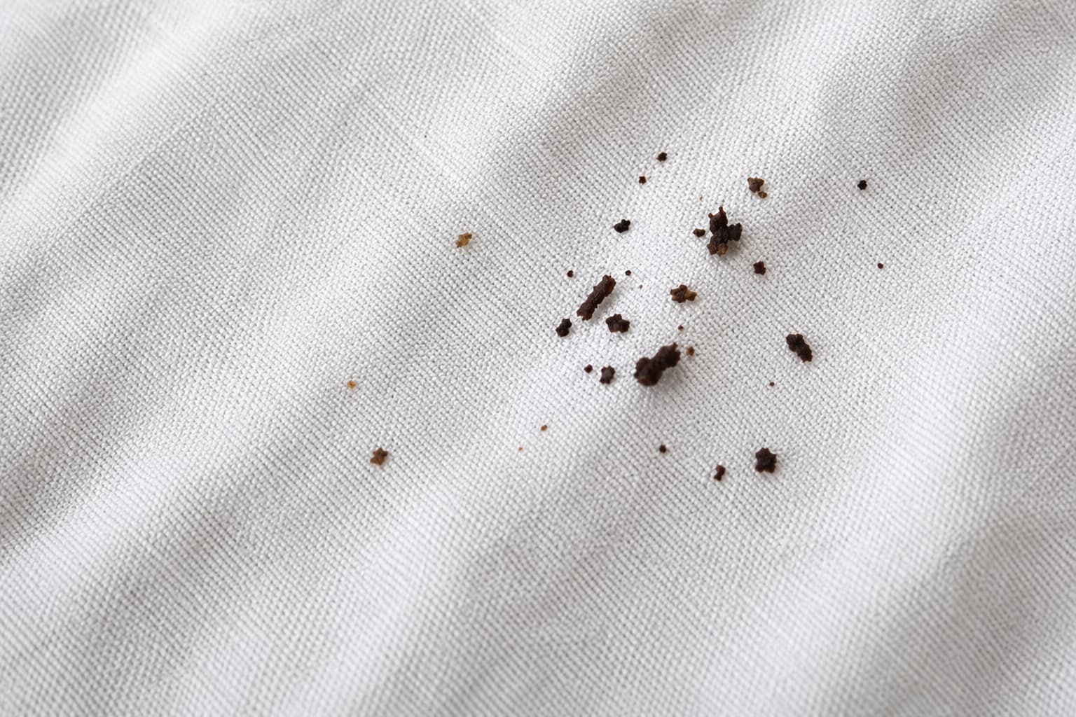 Dark brown spots on white fabric, a warning sign of bed bug activity