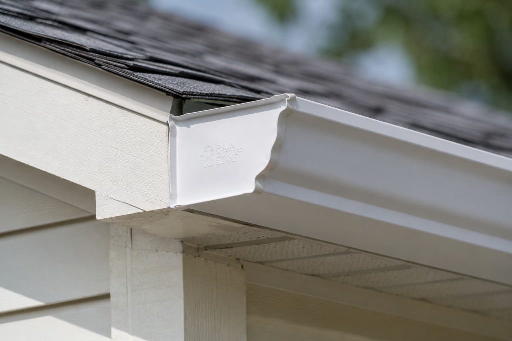 White aluminum gutter end cap installed at the corner of a residential roofline
