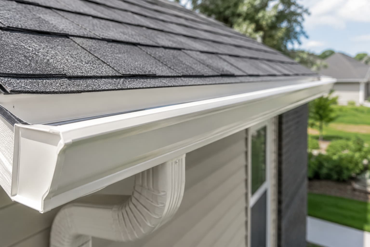 Close-up of a rain gutter properly installed along a residential roofline showing correct positioning past the shingles