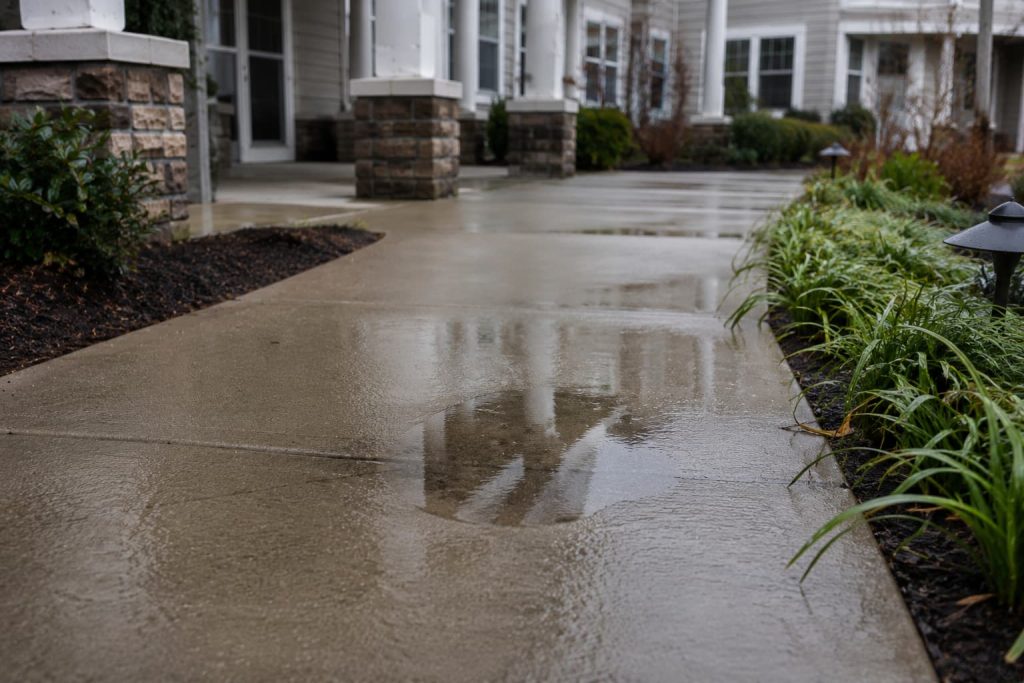 Wet walkway with standing water near a senior living community entrance
