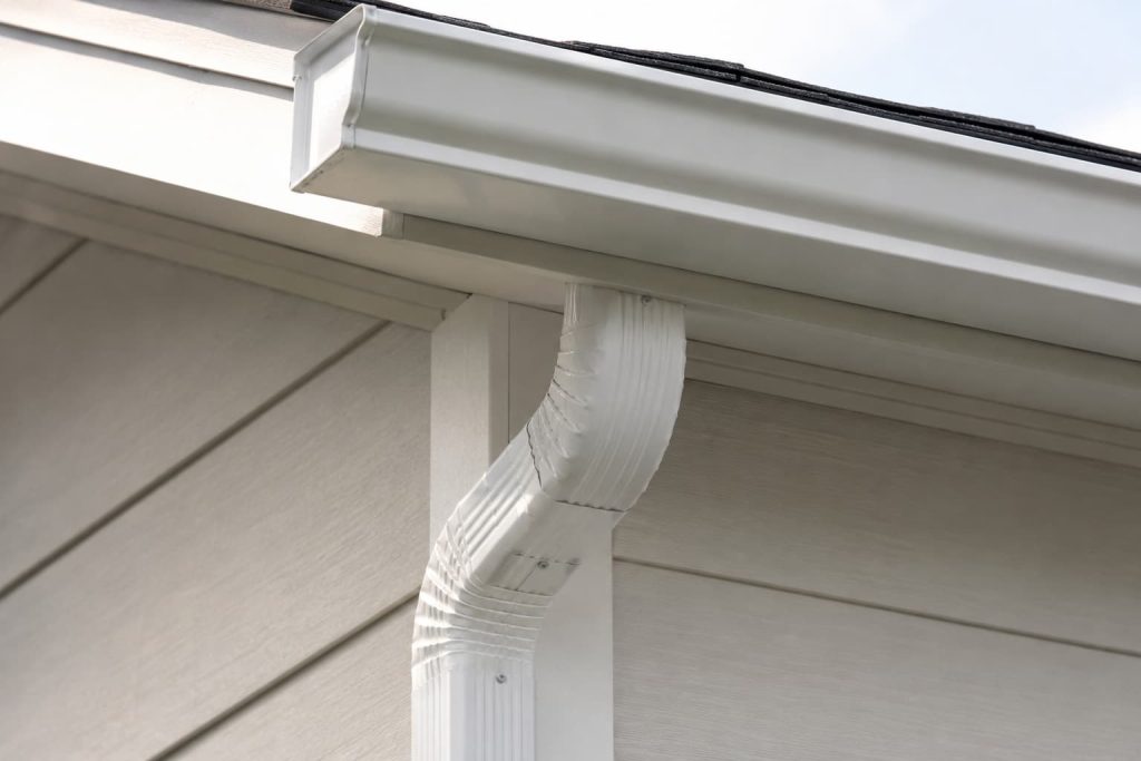 Aluminum gutter components including an end cap and downspout elbow on a residential home exterior