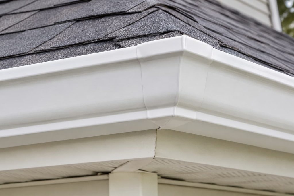 White aluminum gutter corner miter joint connecting two sections of residential gutter