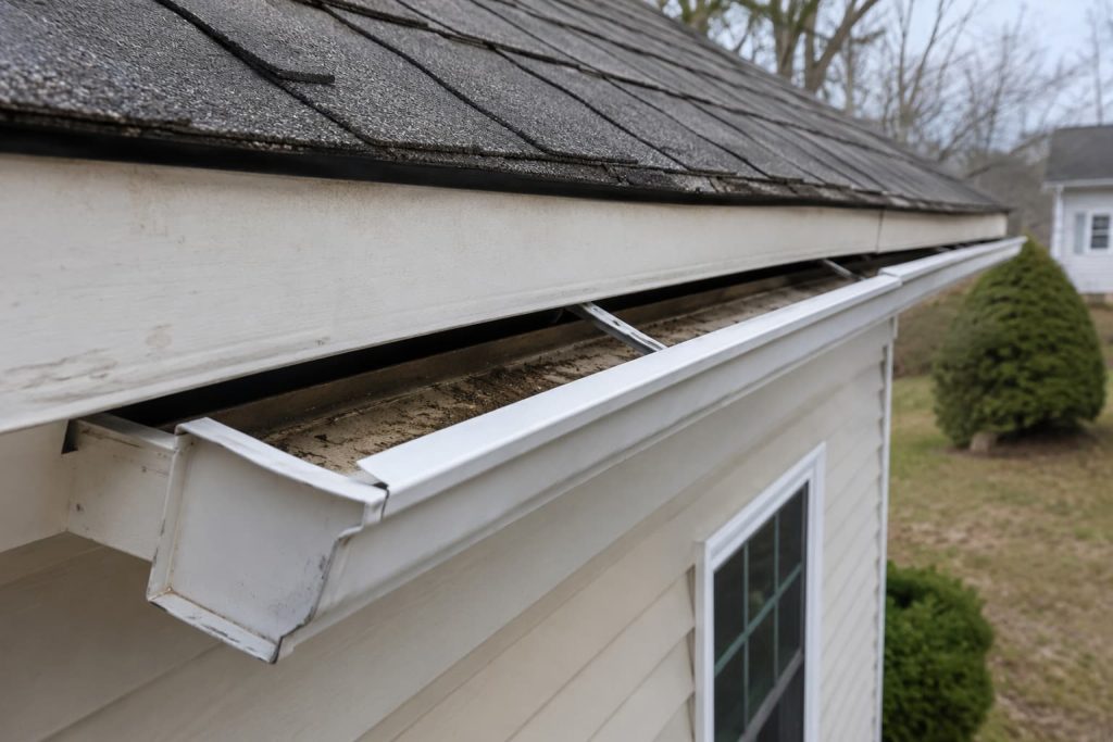 Loose residential gutter pulling away from the fascia board with visible debris buildup
