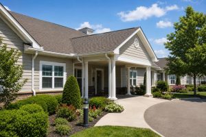 Well-maintained senior living community entrance with clean siding, landscaping, and covered porch