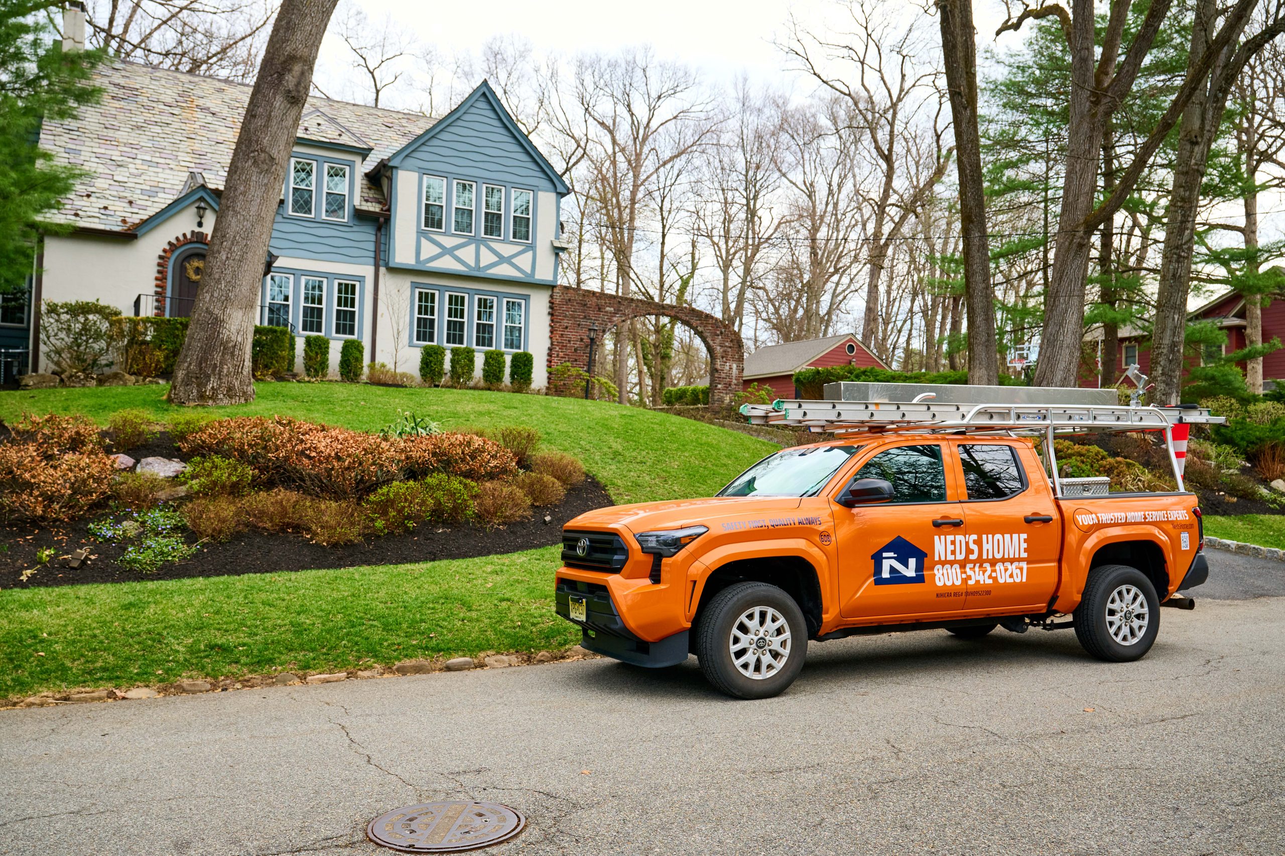 Orange Ned's Home service truck parked in front of a residential home."